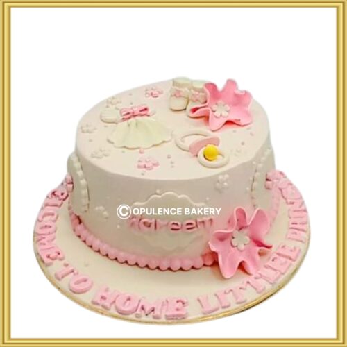 Customized baby shower cake in Lahore with pink fondant booties and dress topper by Opulence Bakery.