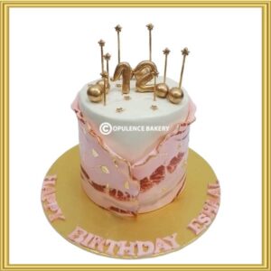 Pink and gold fault line birthday cake in Lahore with metallic star toppers and 12 age number
